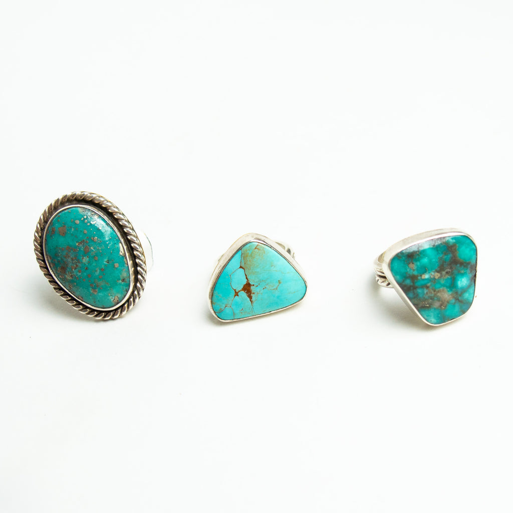 Three large turquoise and silver rings sitting on a white backdrop.