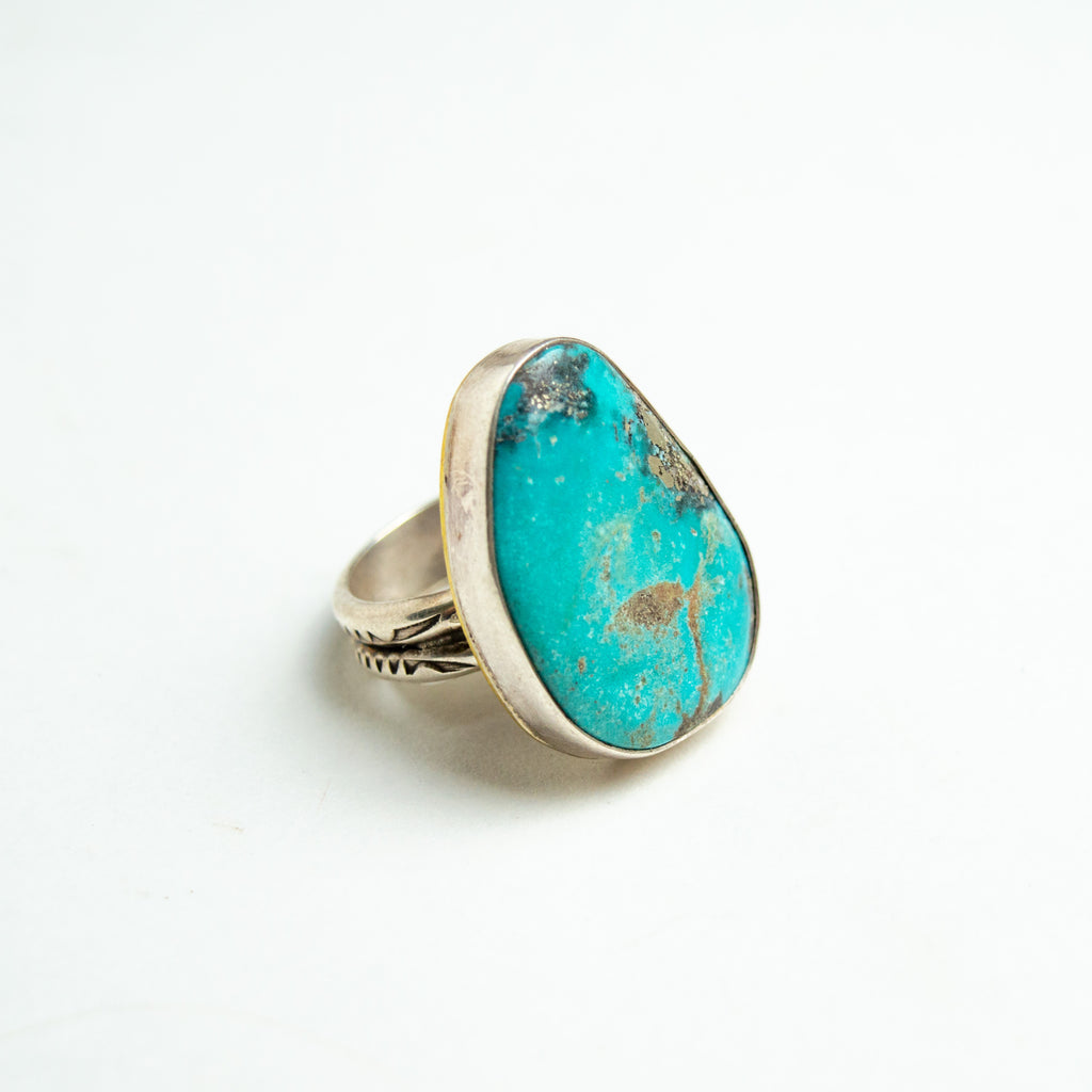 One large turquoise and silver ring sitting on a white backdrop.