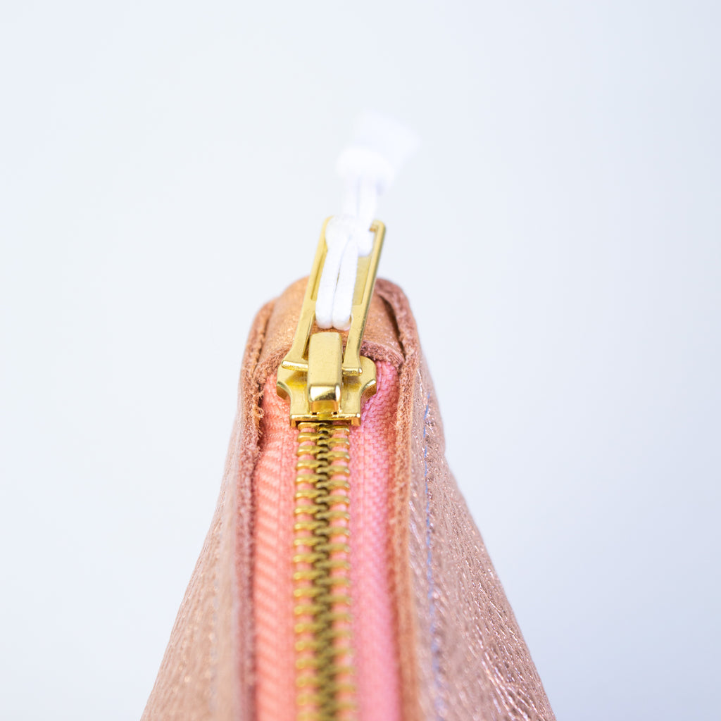 Medium metallic pink pouch, showcasing its gold zipper, white zipper pull, and pink leather zipper catch.