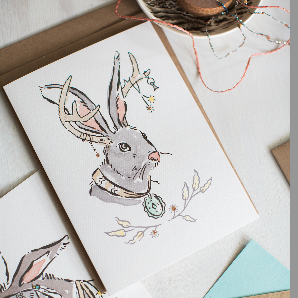 White card with a stylized jackalope. the jackalope is adorned with multiple jewels
