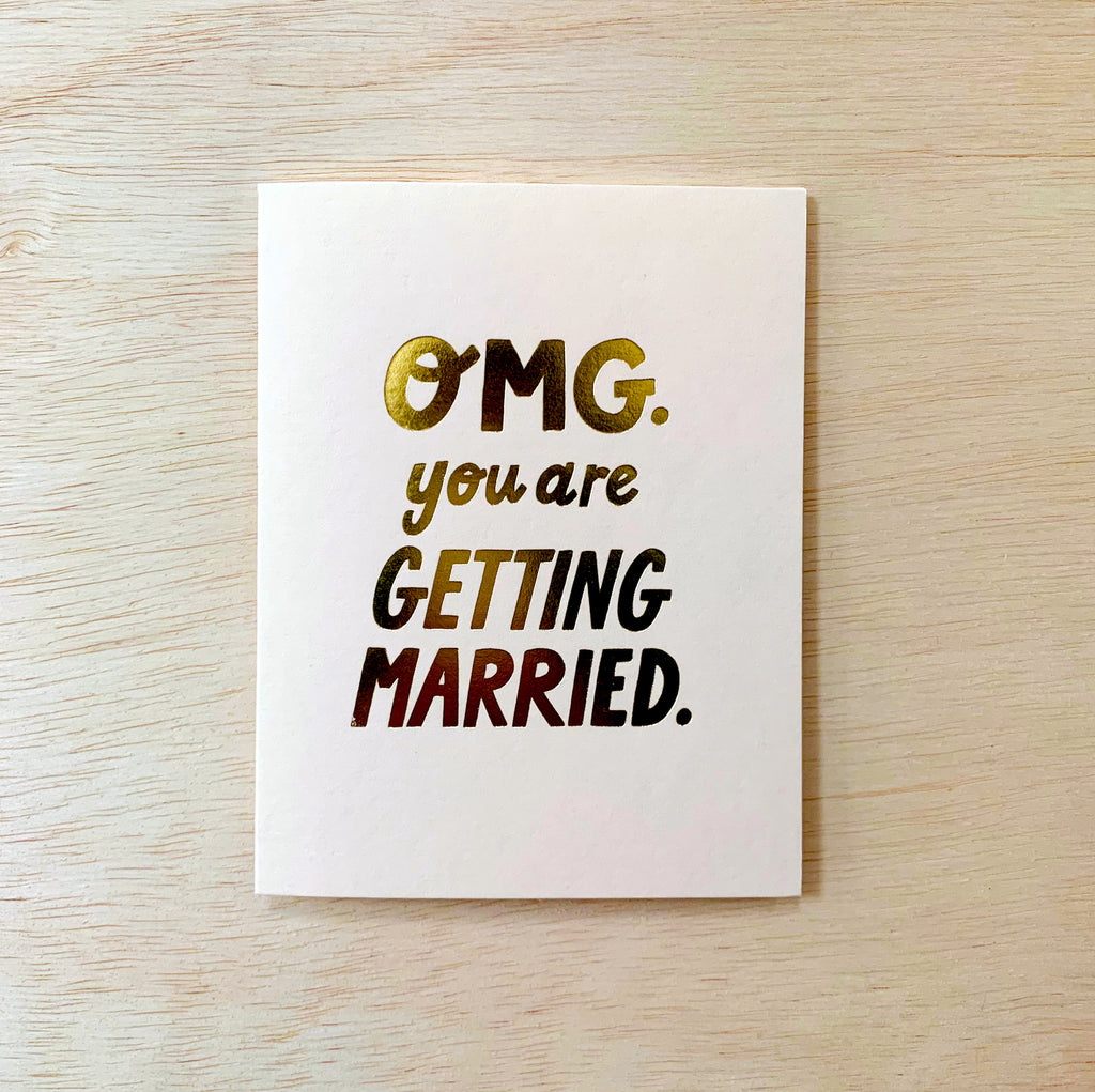 White card with gold text reading "OMG. You are getting married."