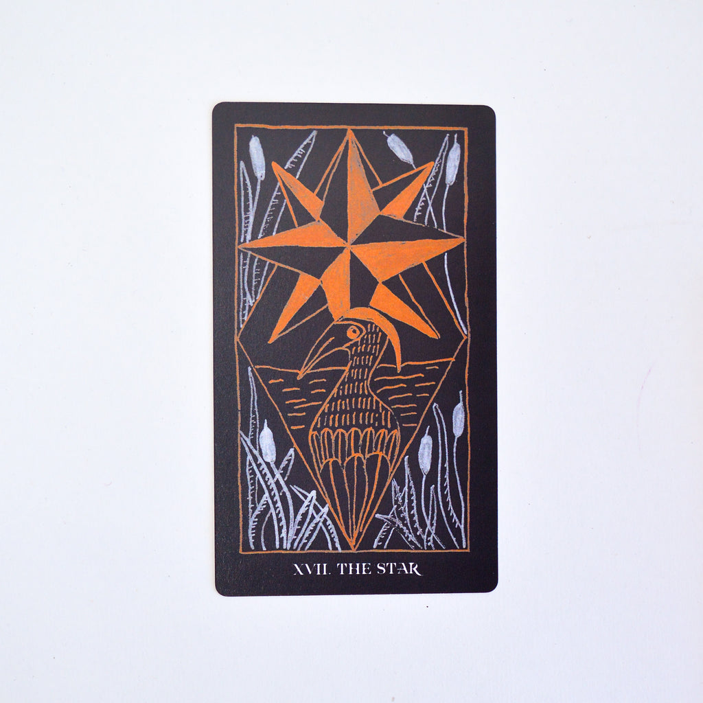 The tarot card "the star" on a white backdrop. There is artwork of a bird with a geometric shape resembling a star above it in orange ink. There are cattails in white ink in each corner.