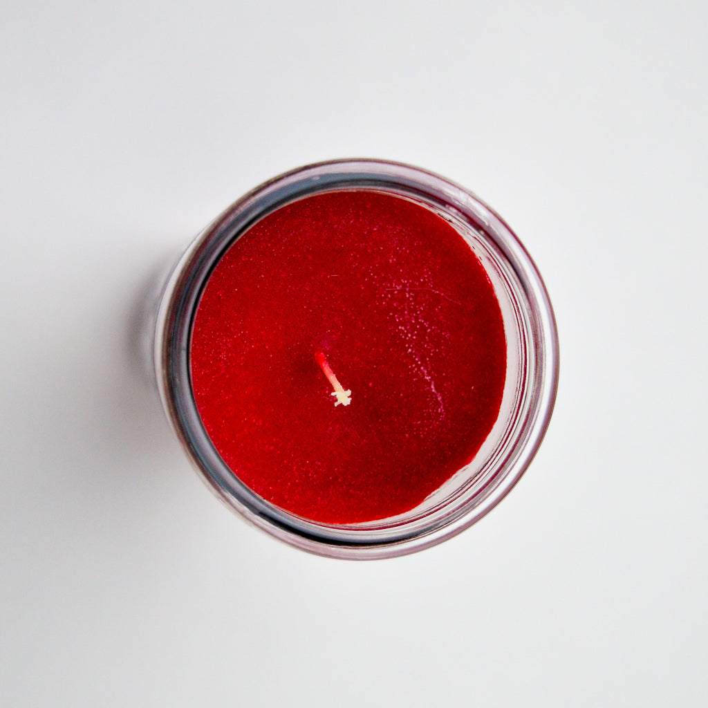 Top dow view of a red candle with a white cotton wick.