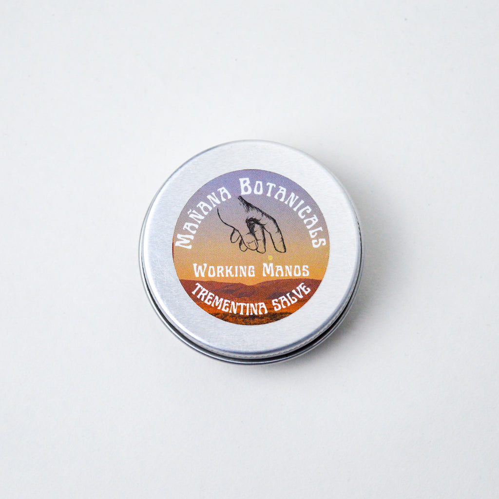 Circular tin with a small circular label. The label has white text reading "Mañana Botanicals, Working Hands, Trementina Salve."