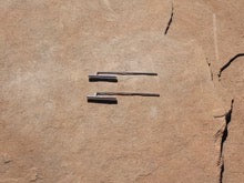 Silver earrings with a long finding. Parallel to the finding is a vertical barbell about half the size.