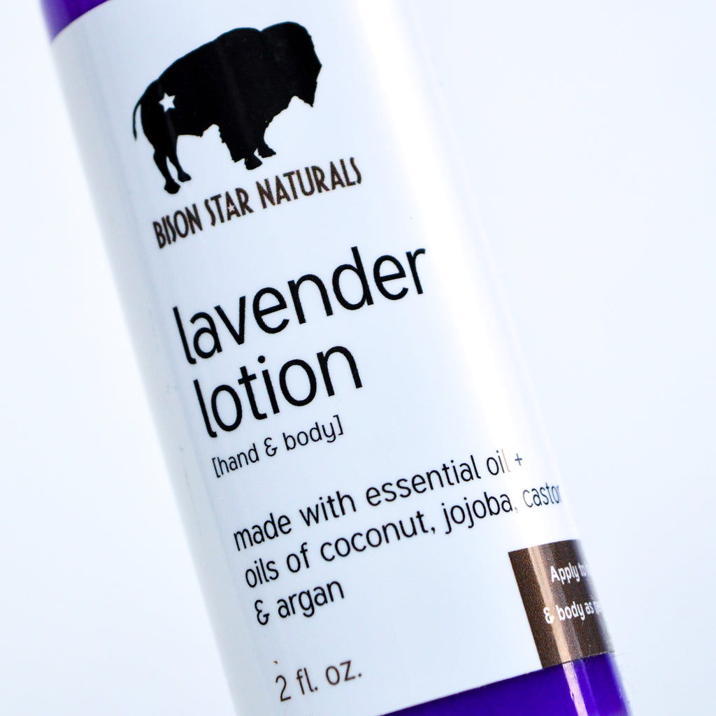A close up of a purple cylindrical lotion bottle with a white label. The label has black lettering on it reading "Lavender lotion [hand & body]" "made with essential oil + oils of coconut, jojoba, castor, and argan" "2 fl. oz."