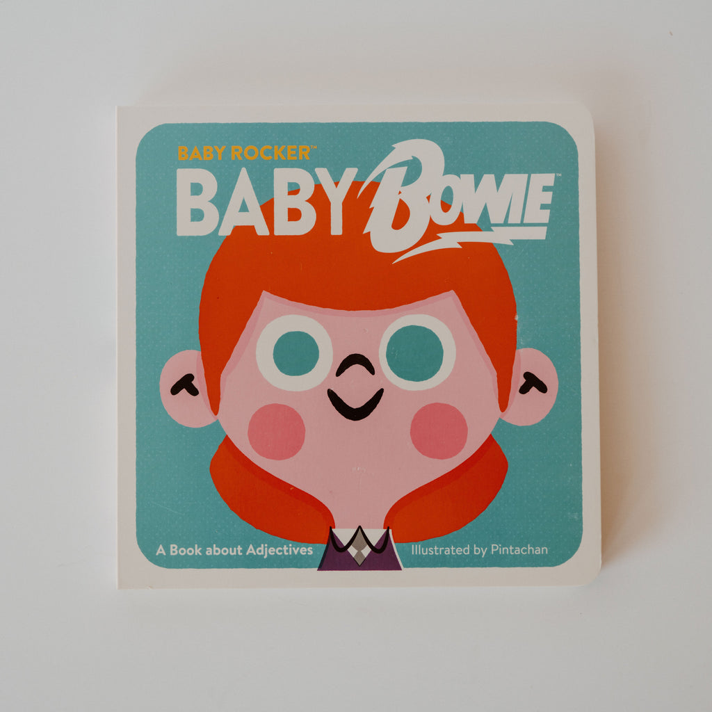 A cover of the book "Baby Rocker: Baby Bowie." Illustrated by Pintachan. The cover is an illustration of a baby David Bowie. Additional text reads "A Book about Adjectives."