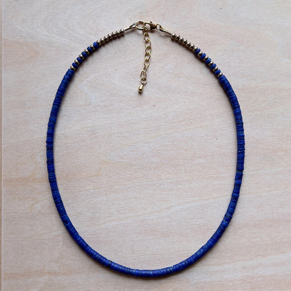 A lapis necklace laying on wood. 
