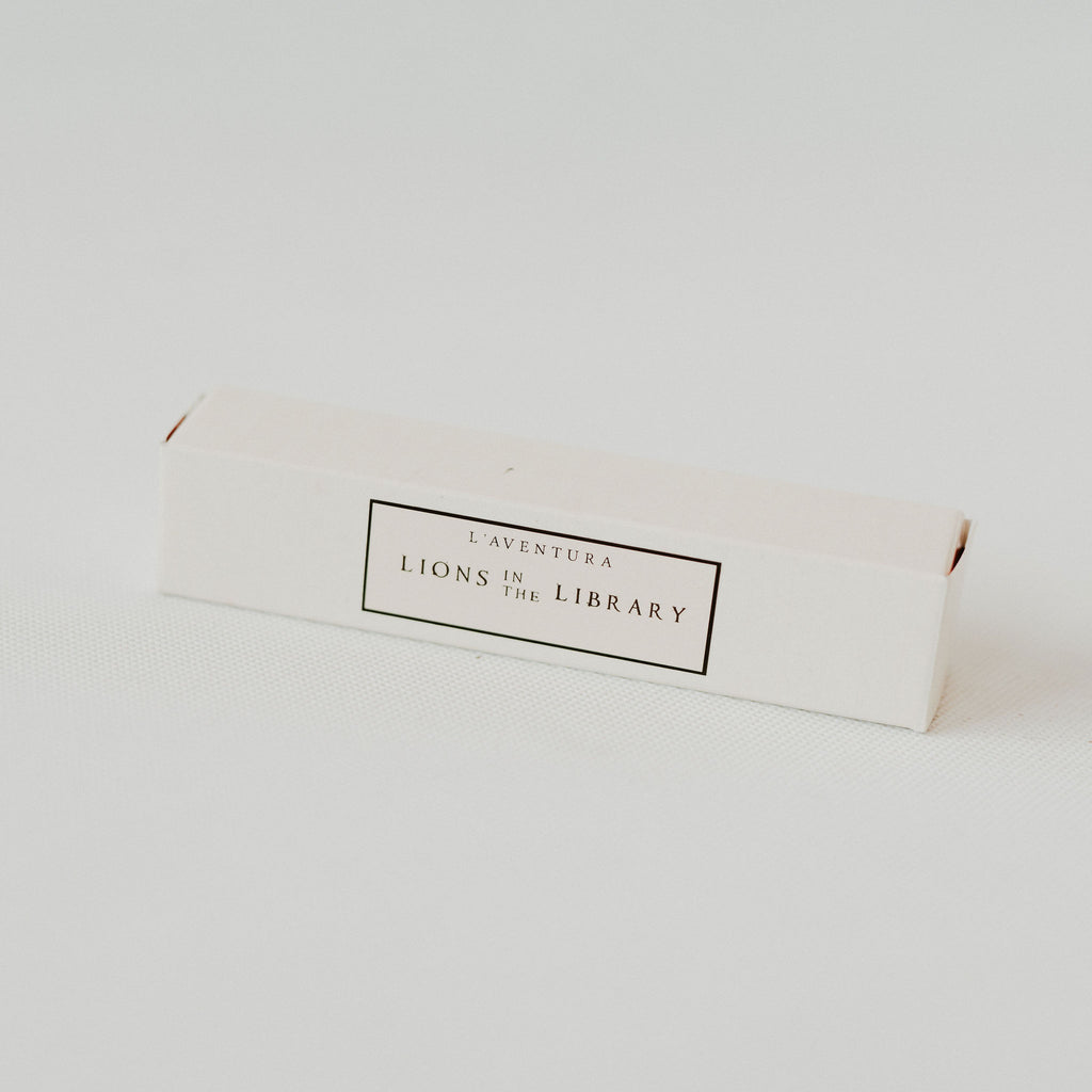 A perfume box laying on a white backdrop.