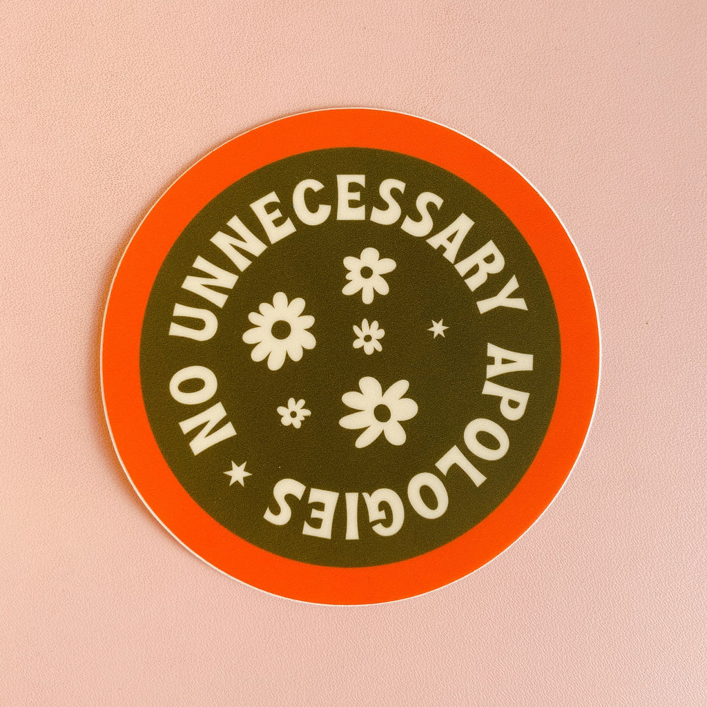 Circular sticker with an orange boarder and army green middle. there are white flowers in the middle with white text around it reading "No unnecessary apologies."