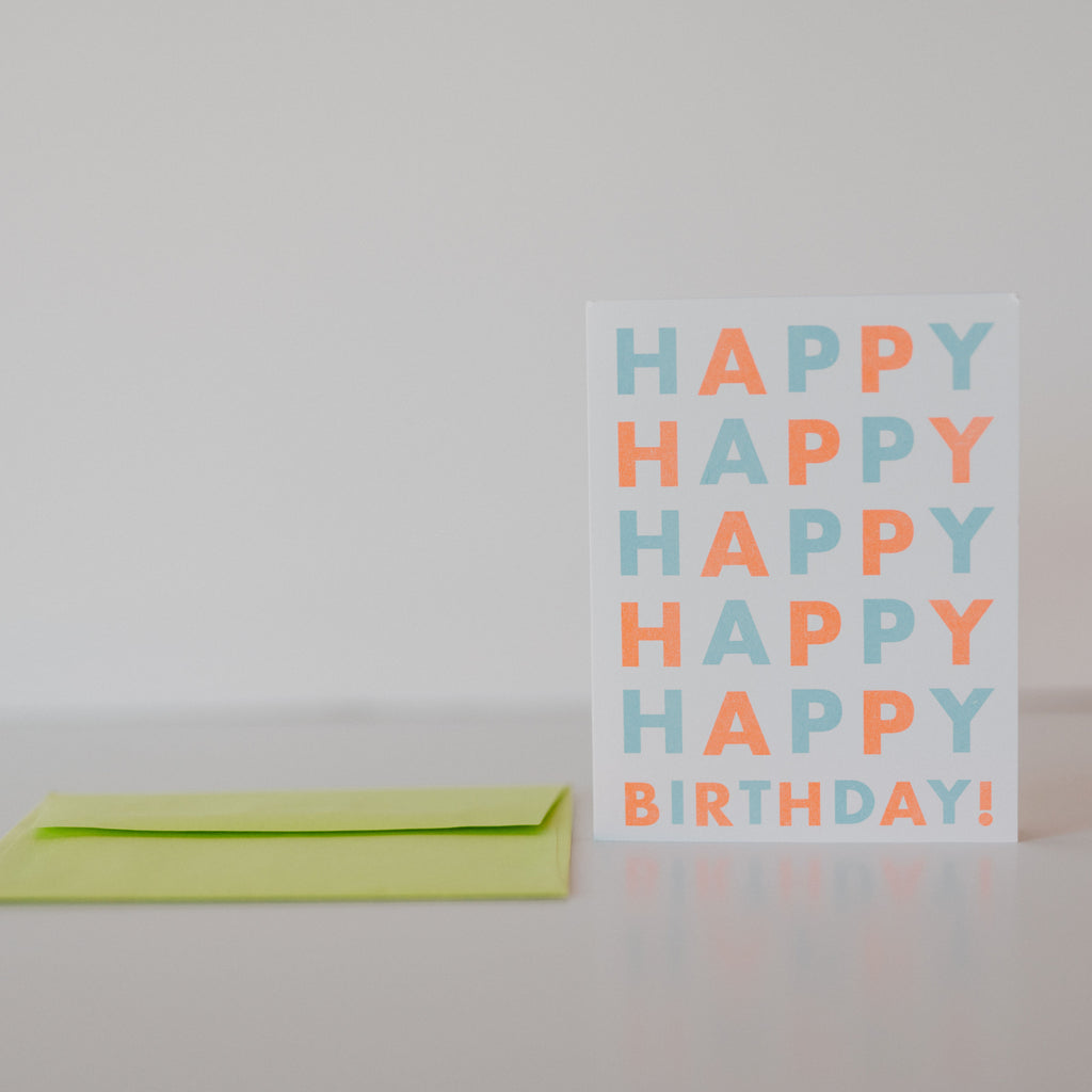 White card with a green envelope, the card has happy birthday written on it with the word happy being repeated five times before being followed by birthday.