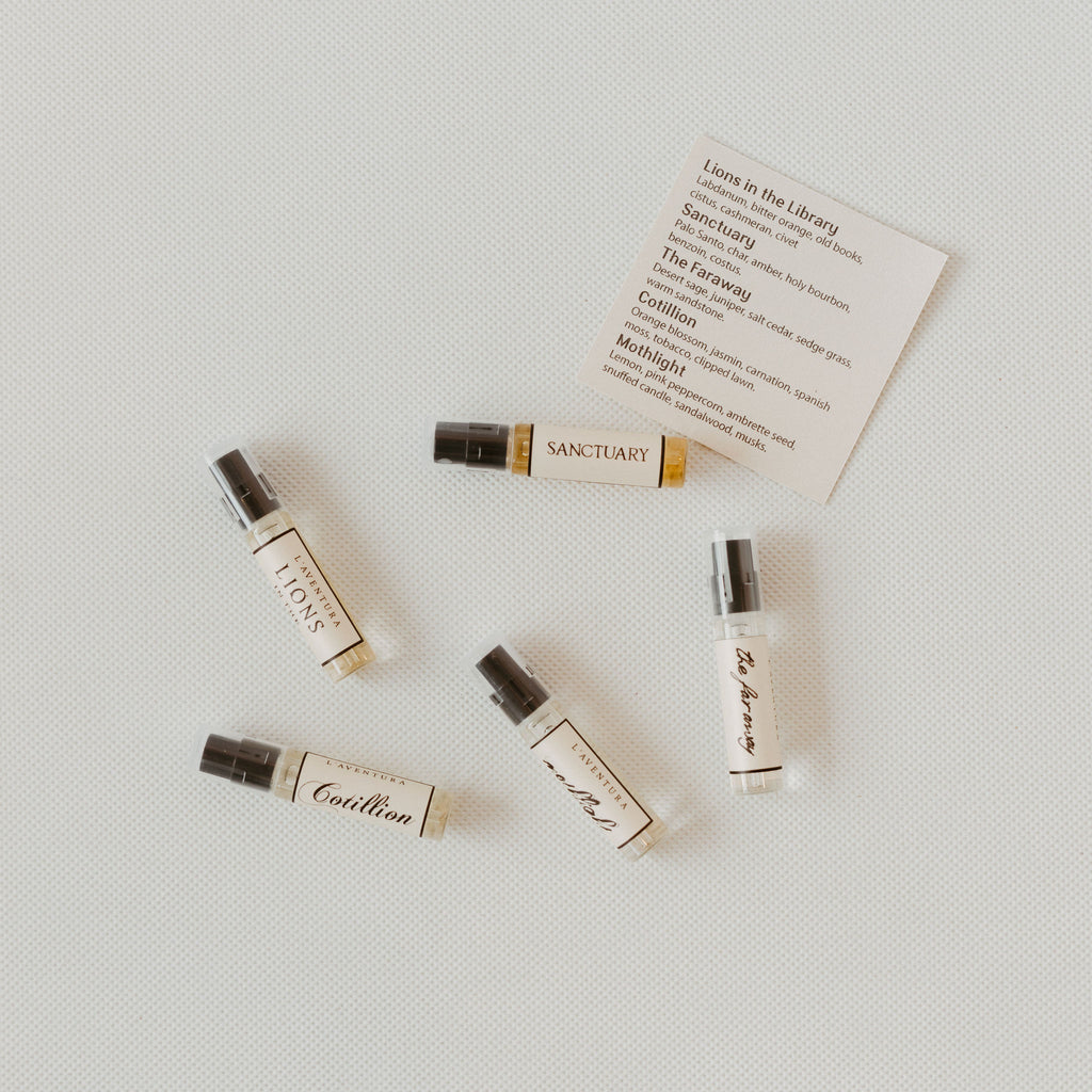 Five small bottles of perfume next to a detail card which has the names of the perfumes and descriptions of each.
