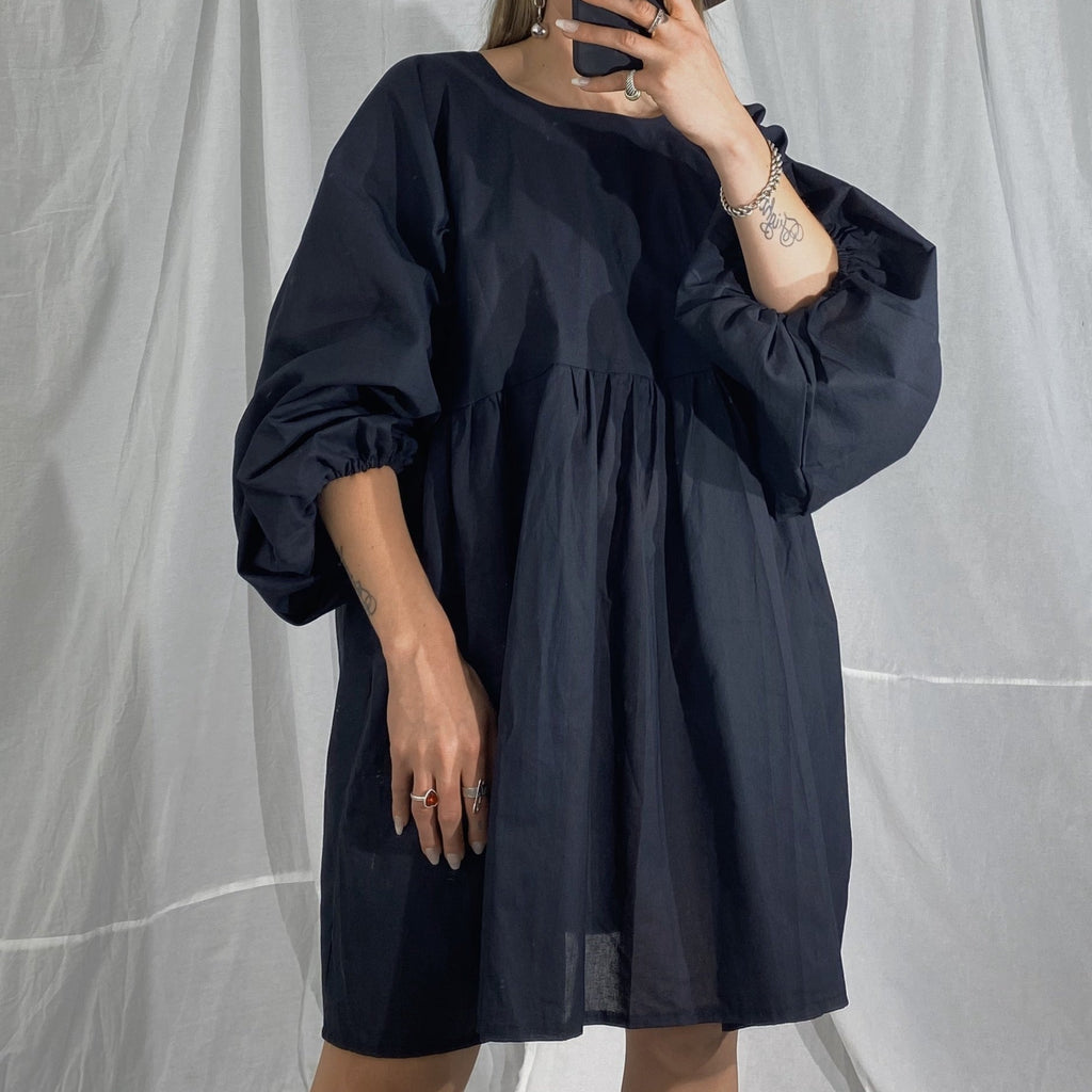 Flowing mini dress in black. Has long puffy sleeves that bunch up around the cuffs.