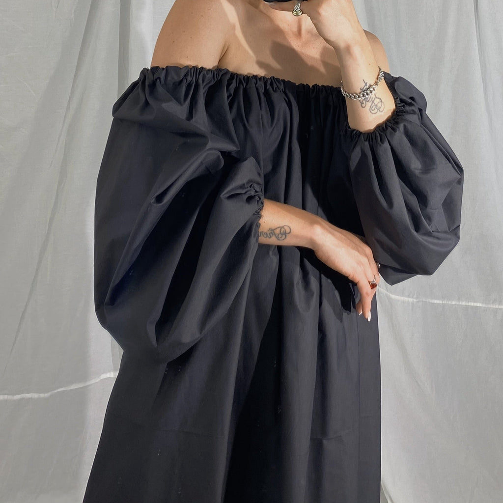 A person wearing a long puffy sleeved maxi dress in black.