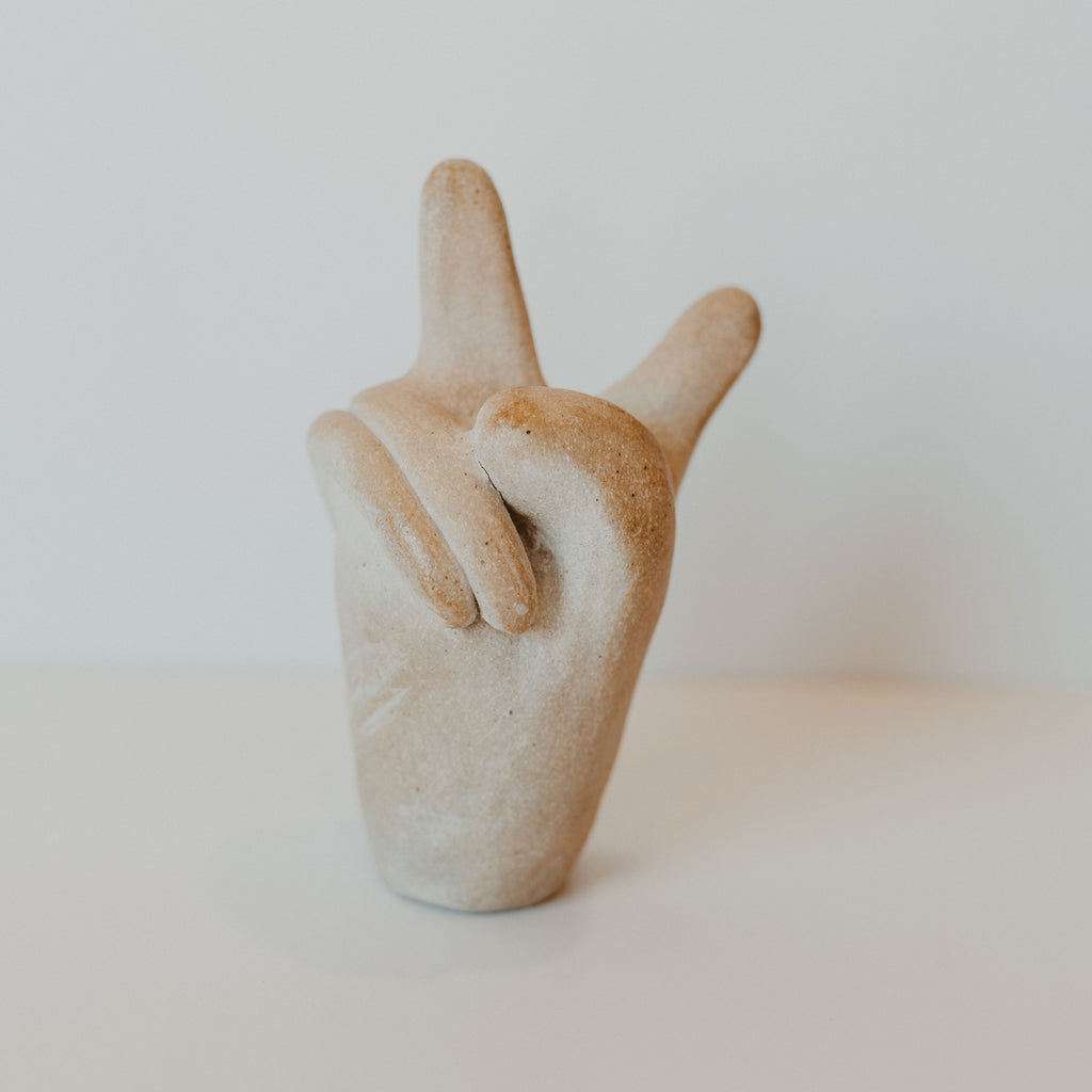 Beige ceramic peace sign hand.
