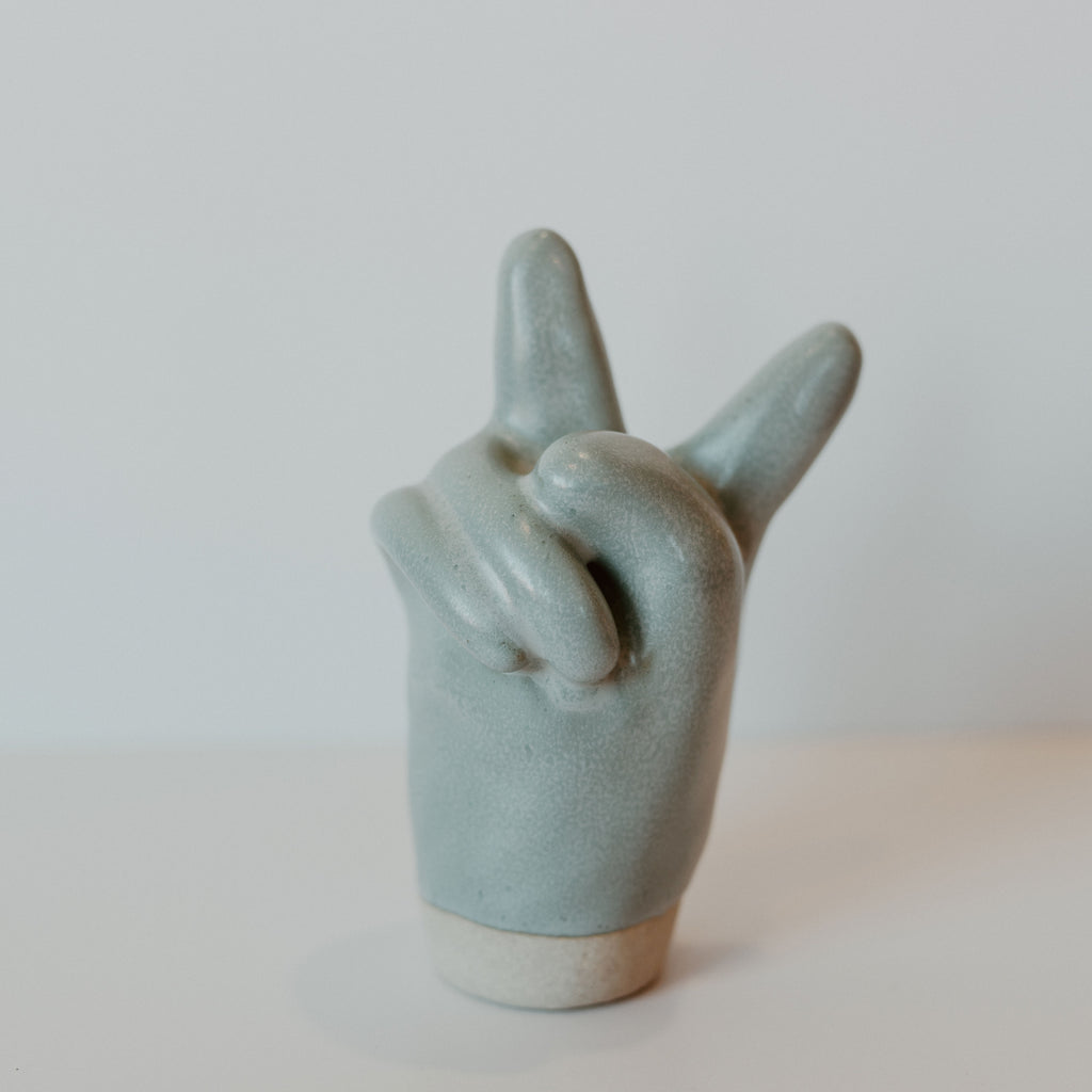 Blue ceramic peace sign hand with a grey band at the bottom.