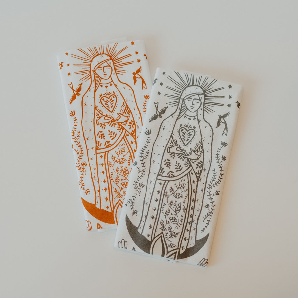 two hand towels with our lady Guadalupe, one with orange ink and one with grey ink.
