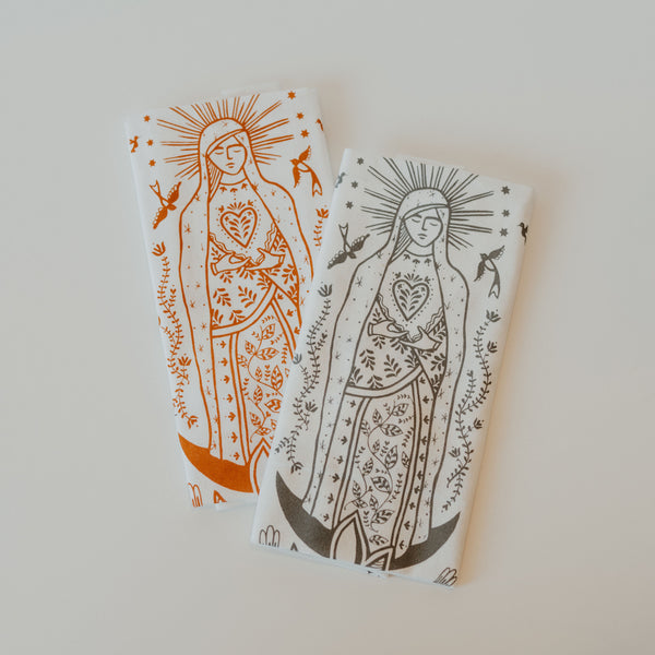 two hand towels with our lady Guadalupe, one with orange ink and one with grey ink.