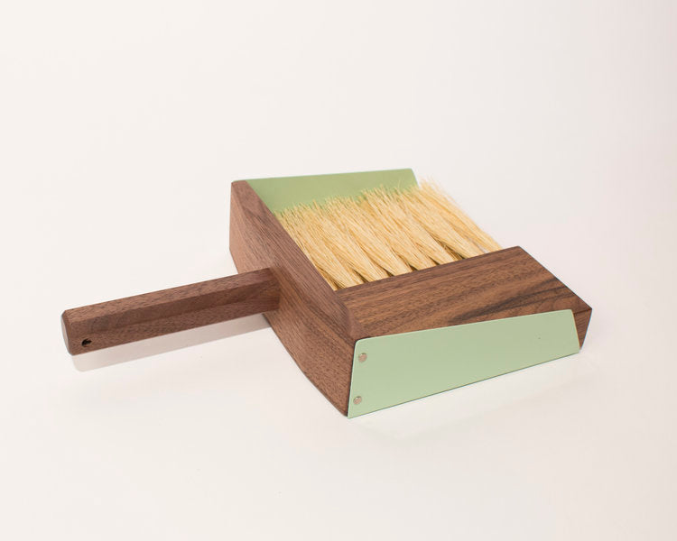 Dark wood hand broom and dustpan with green metal sides and blonde horse hair bristles.