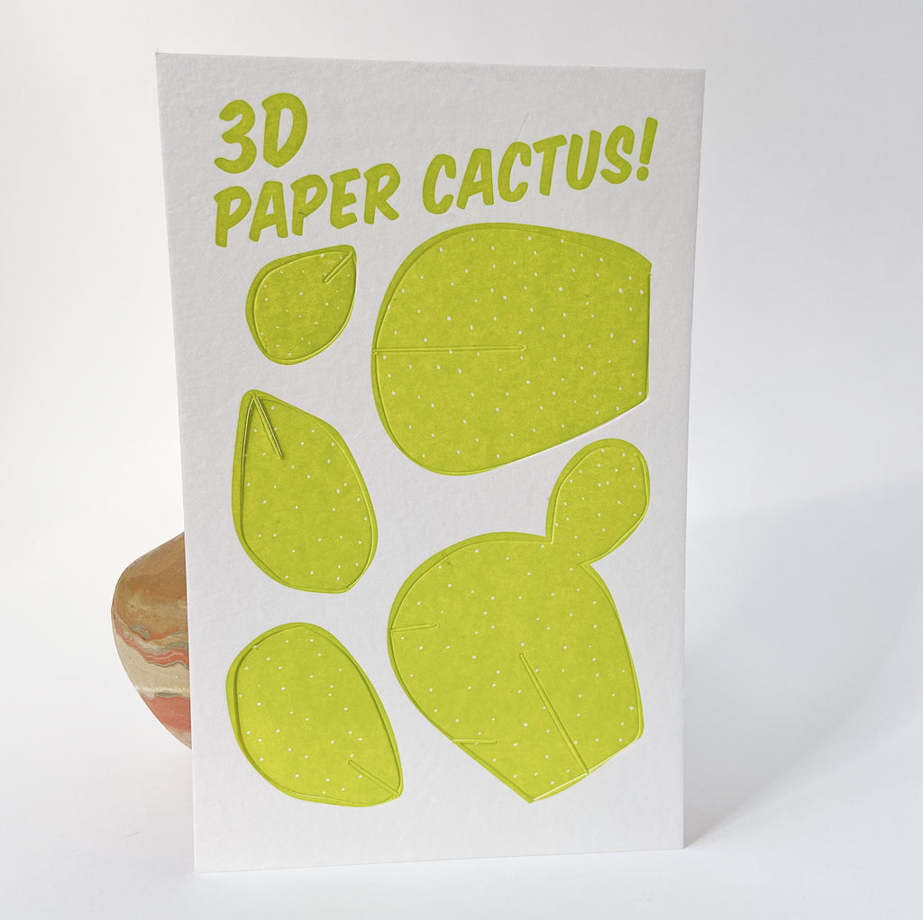 Thick cotton paper with "3D Paper Cactus!" printed at the top against a white background. 5 perforated paper green cactus pieces of varying sizes follow down the card.