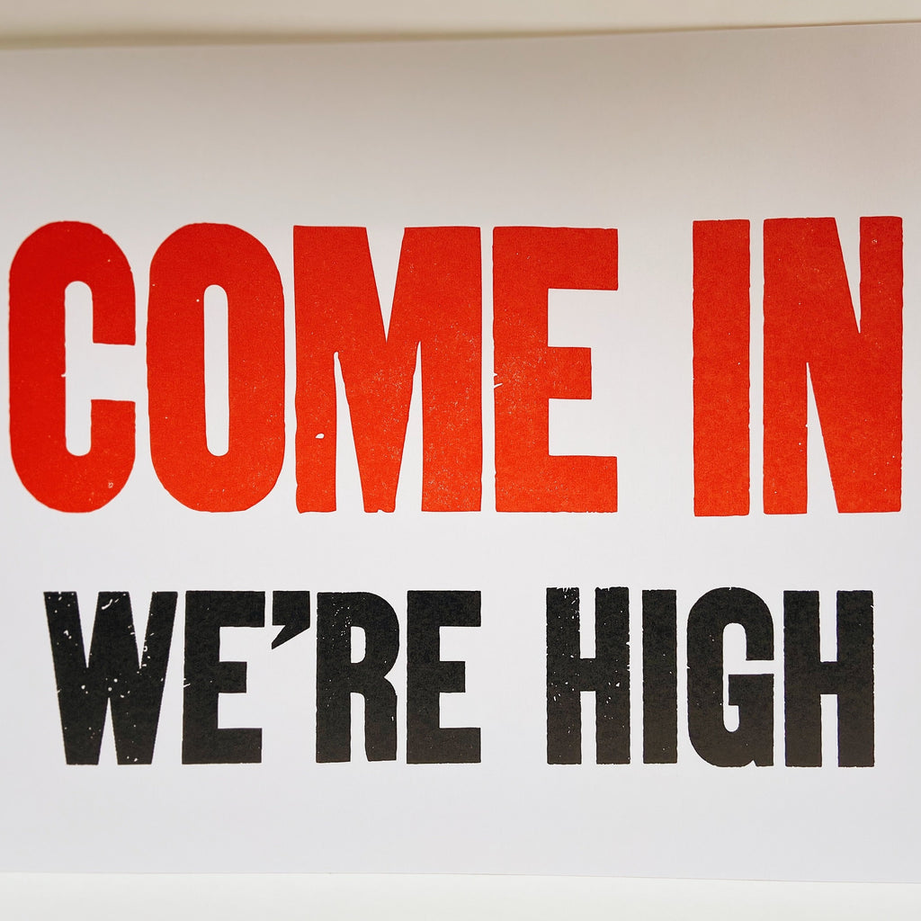 Art print with a white background and red and black lettering reading "COME IN WE'RE HIGH."