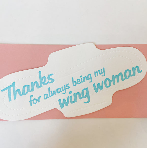 White card shaped like a pad with blue text reading "Thanks for always being my wing woman."