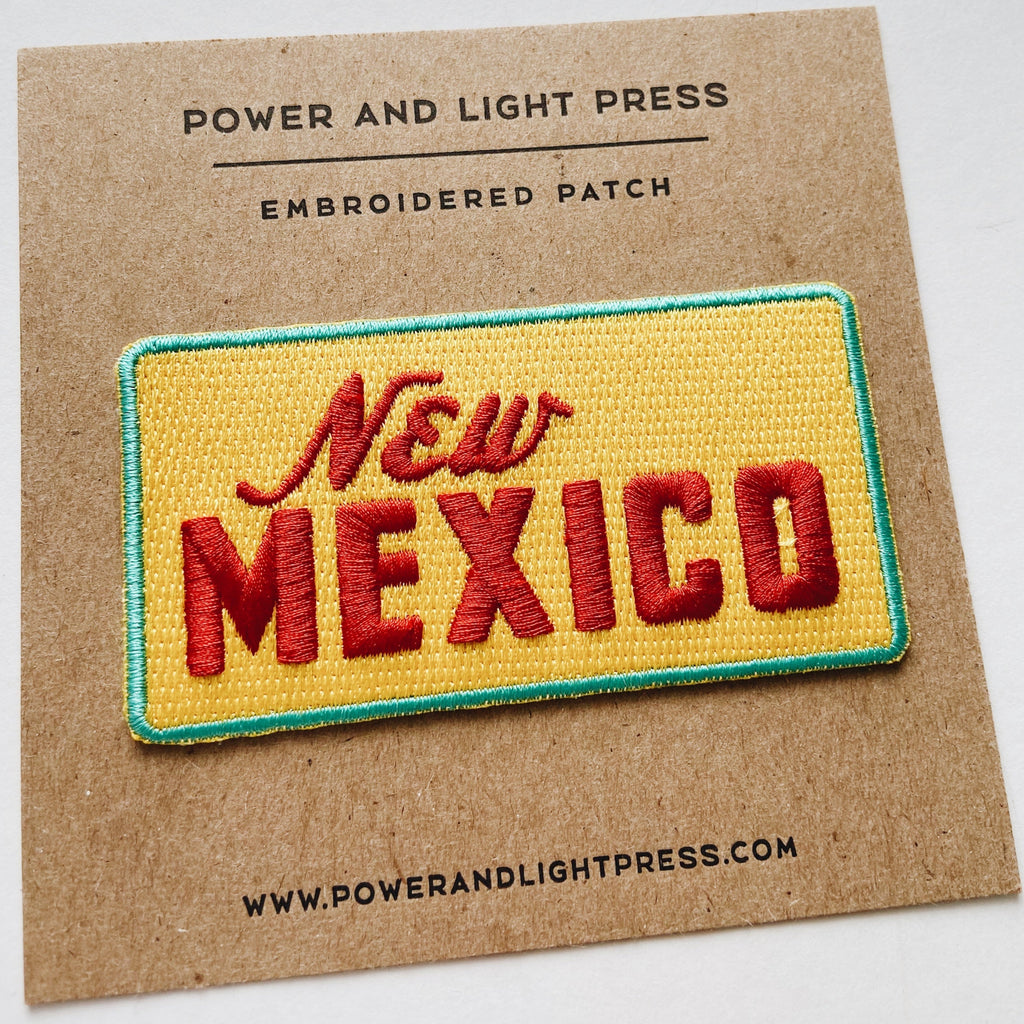 yellow embroidered patch with a turquoise boarder and red text in the middle reading "New Mexico."