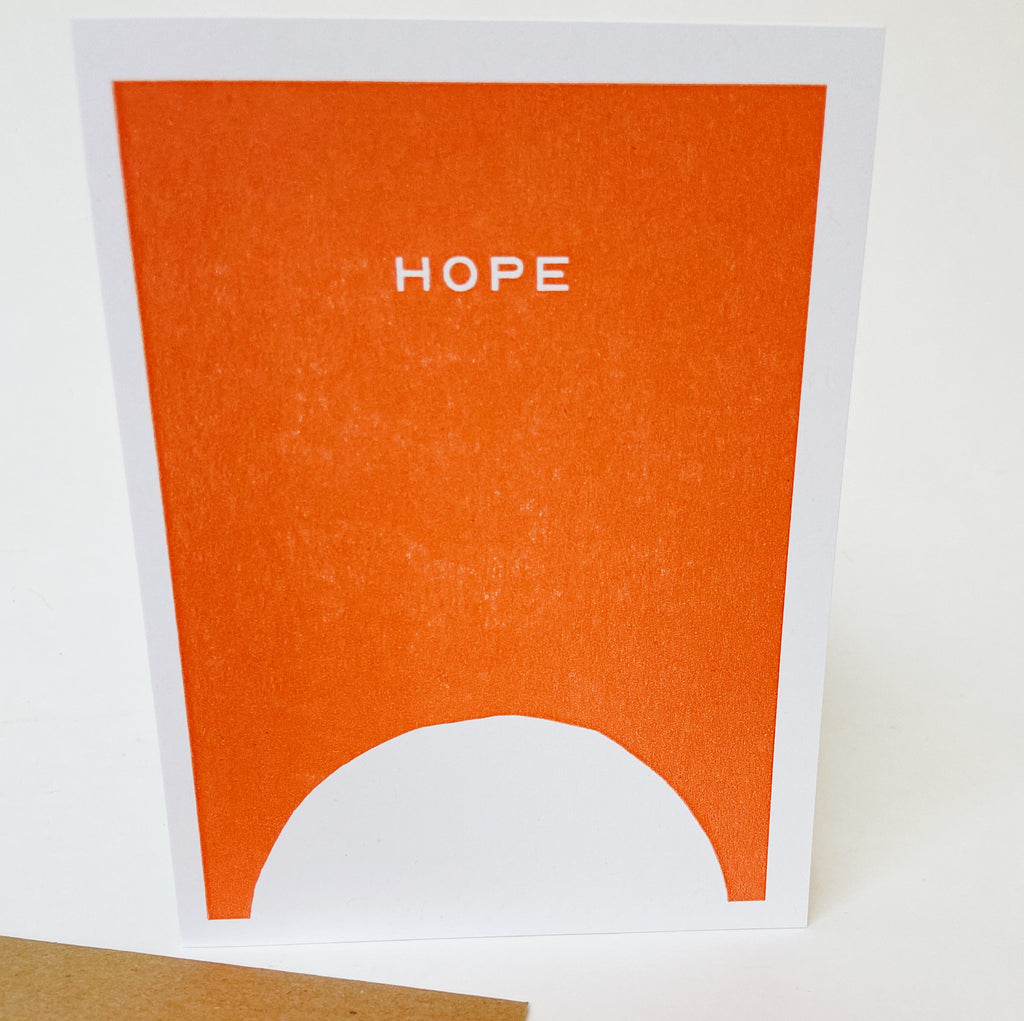 Orange card with a white boarder and white semicircle at the bottom. The middle of the card has white text reading "Hope"