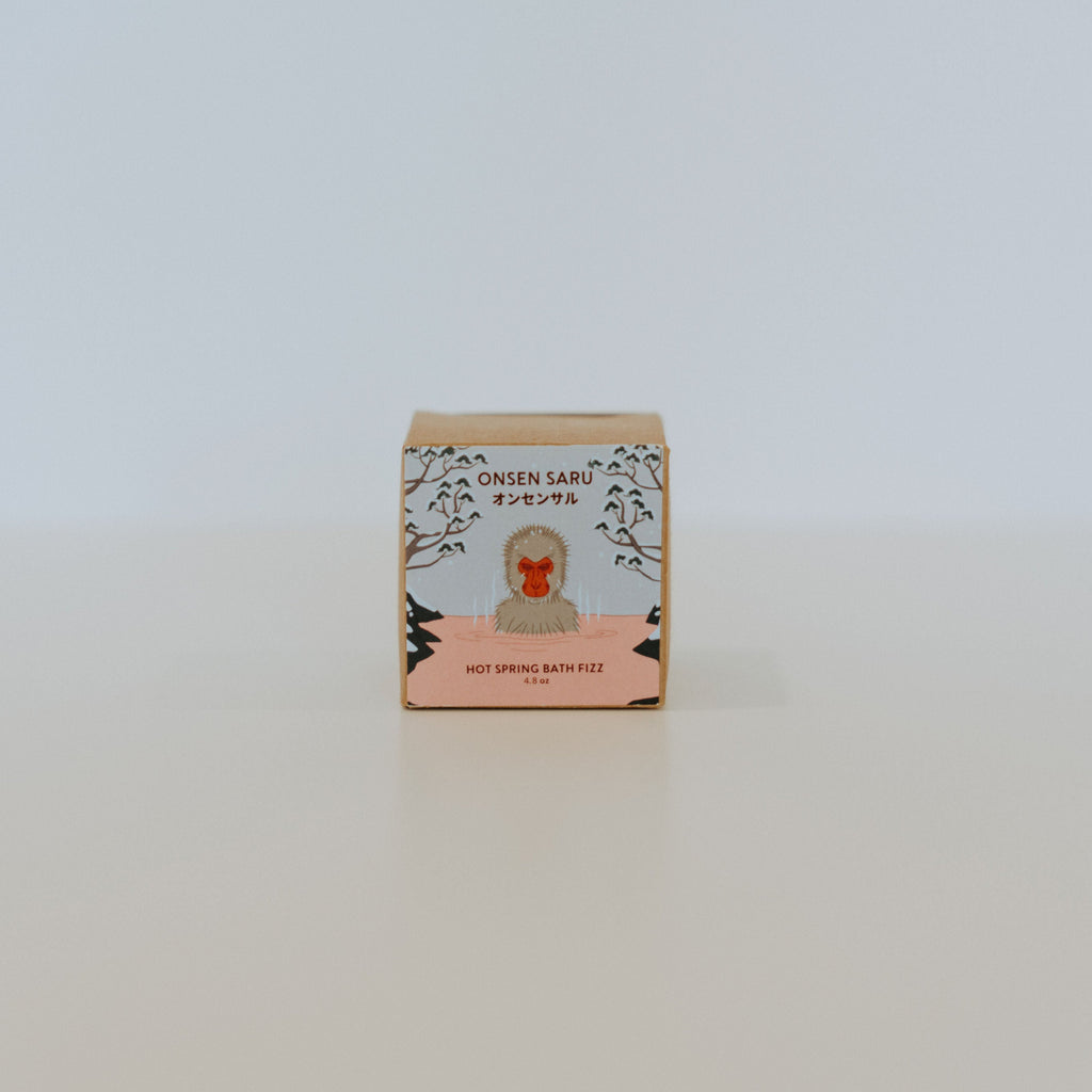 Small square box with a blue and pink label and black text reading "Onsen Saru, hot spring bath fizz." 