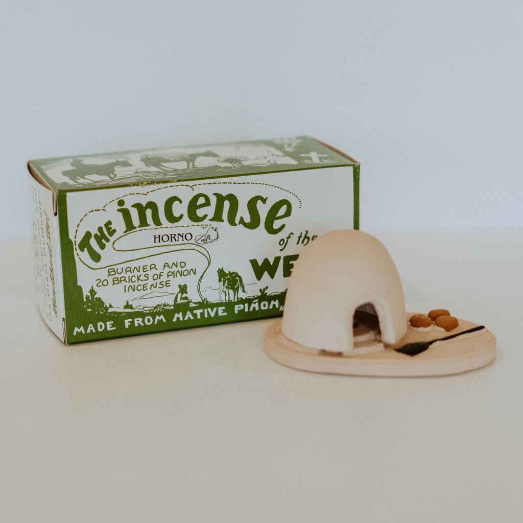 Small, rectangular cardboard box with text reading "The incense of the west. Made from native piñon." In front of the box is a small ceramic horno.